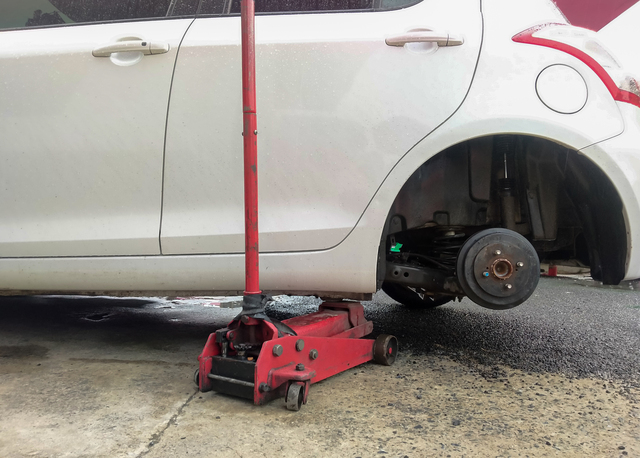 White cars change wheels using a lifting jack.